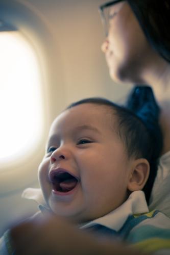 9 month old mixed race baby boy travels with his mother on a commercial aeroplane flight - Australian Stock Image