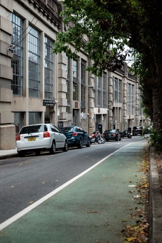A bicycle lane and a warehouse conversion block under the train tracks in North Sydney with cars - Australian Stock Image