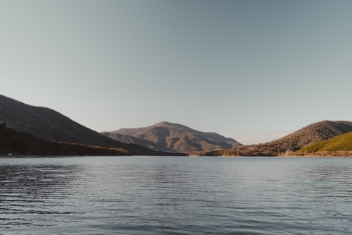 A blue lake with mountains in the background after sunrise - Australian Stock Image