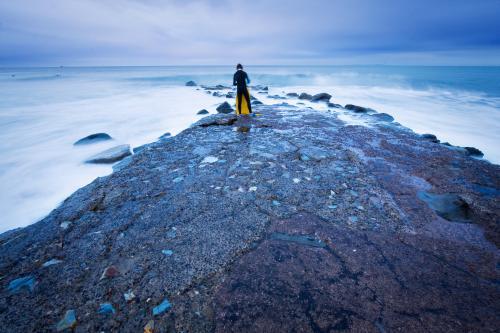 A boogie board rider walks out into the rough seas - Australian Stock Image