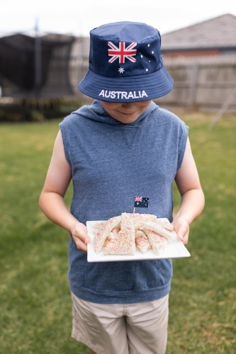 A boy holding a white plate of iconic traditional Australian fairy bread with an aussie flag - Australian Stock Image