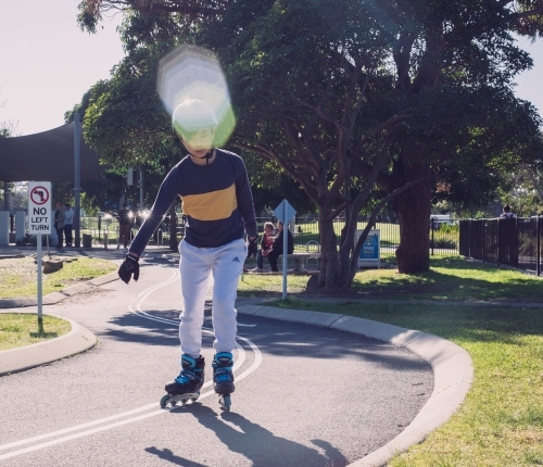 a boy inline skating at the park with rollerblades - Australian Stock Image