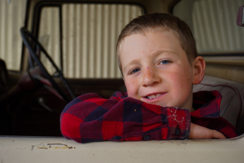 A boy resting on an elbow on the windowsill of an old truck - Australian Stock Image