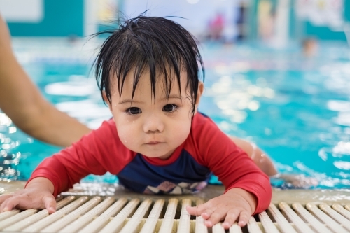 a boy toddler climbing up the pool - Australian Stock Image