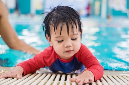 A boy toddler crawling by the pool - Australian Stock Image