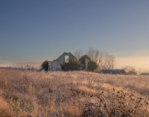 A broken down building in a frosty field under a blue sky - Australian Stock Image