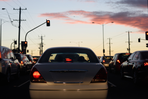 A busy street during evening rush hour with a background of car taillights and a sunset sky - Australian Stock Image