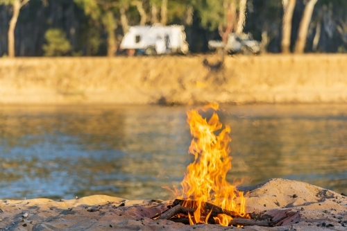 A camp fire burning on a river bank - Australian Stock Image