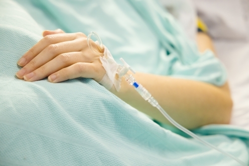 A cannula in the left wrist of a female patient lying on a bed - Australian Stock Image