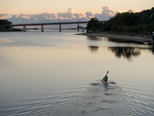 A canoe paddling down a river in the early morning - Australian Stock Image