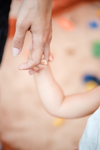 a child holding the hand of an adult - Australian Stock Image