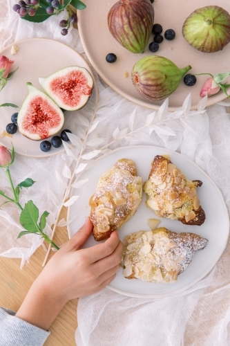 A Child's Hand Eating Snacks Almond Croissants