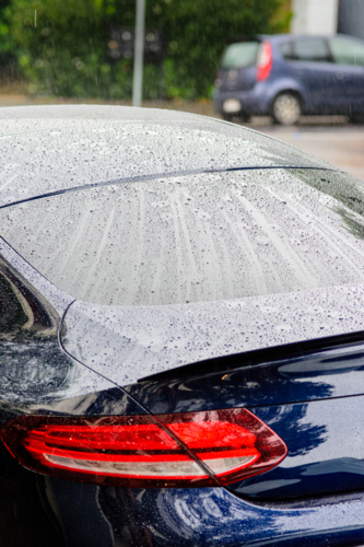 A Close up of Water Droplets on a Car's Back Window on a Rainy Day - Australian Stock Image