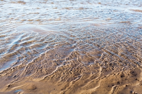 A close up of water ripples of a river at low tide.