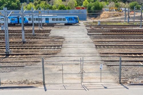 A commuter train on a crossing behind a high gate - Australian Stock Image