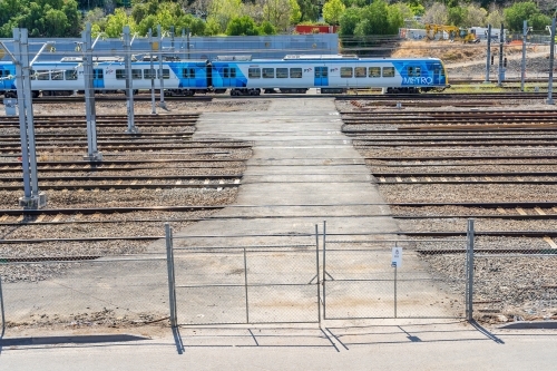 A commuter train on a crossing behind a high gate - Australian Stock Image