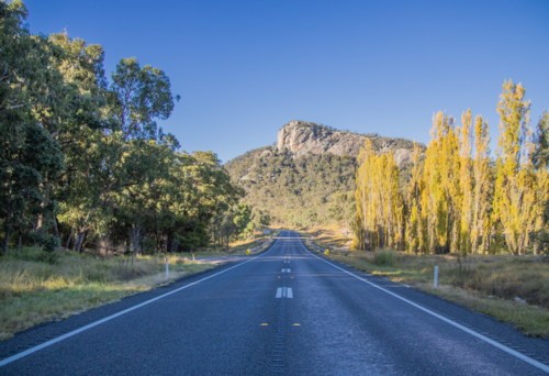 A country highway, autumn poplars and a granite monolith - Australian Stock Image