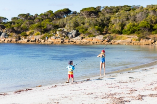 a couple of little kids fishing on the beach - Australian Stock Image