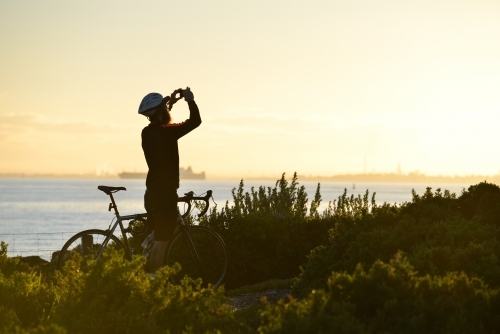 A cyclist stops to take a photo on his mobile phone - Australian Stock Image