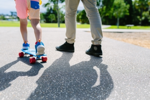 Dad teaching his son how to ride a skateboard - Australian Stock Image