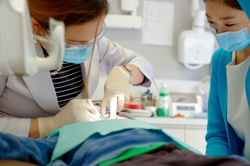 A dentist and her assistant attending to a patient - Australian Stock Image