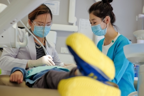 A dentist and her assistant attending to a patient - Australian Stock Image