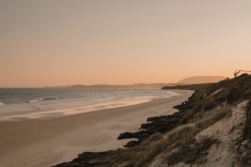 A deserted beach and headland during sunset. - Australian Stock Image