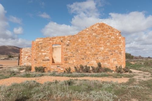 A dilapidated brick building standing alone in an open field. - Australian Stock Image