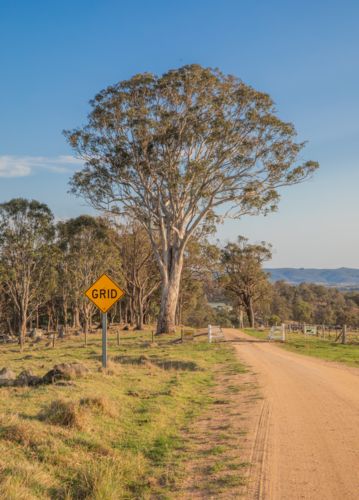 A dirt country road and a cattle grid crossing under a blue sky - Australian Stock Image