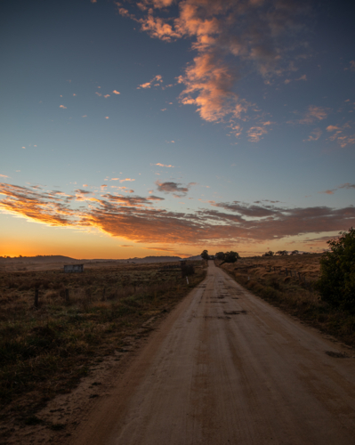 A dirt country road in the country under a colourful dawn sky - Australian Stock Image