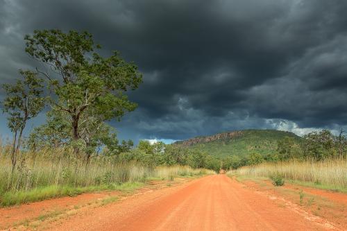 A dirt road through Southern Kakadu with storm clouds - Australian Stock Image