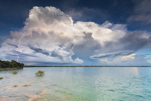 A distant thunderstorm over the ocean with lightning strike - Australian Stock Image
