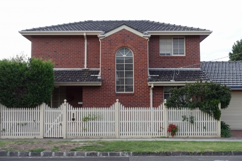 A double story suburban brick home with picket fence - Australian Stock Image