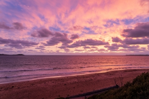 A dramatic colourful sunset over the ocean between two distant land points - Australian Stock Image