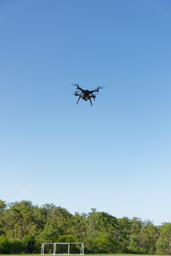 A drone, or UAV, or RPAS hovering over a football field - viewed close up unmanned aerial vehicle - Australian Stock Image