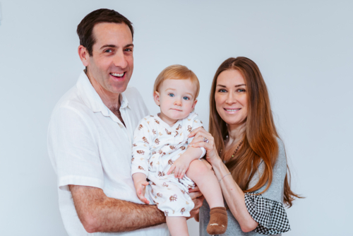 A family portrait of a mid-aged couple and their young boy, smiling against a white background - Australian Stock Image