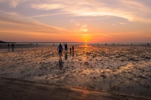 A family silhouetted in the sunset at a beach - Australian Stock Image
