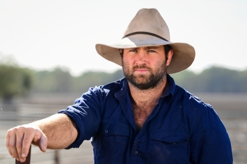 A farmer leans on an iron post during the drought - Australian Stock Image