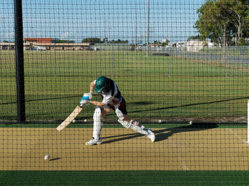 A female cricketer batting in the nets with intention - Australian Stock Image