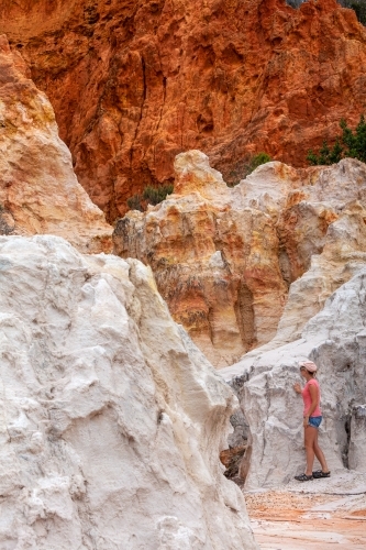 A female explores the Pinnacles a combination of white sands and red clay. - Australian Stock Image