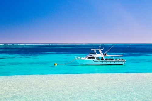 A fishing and diving tour boat on a mooring behind Ningaloo Reef - Australian Stock Image