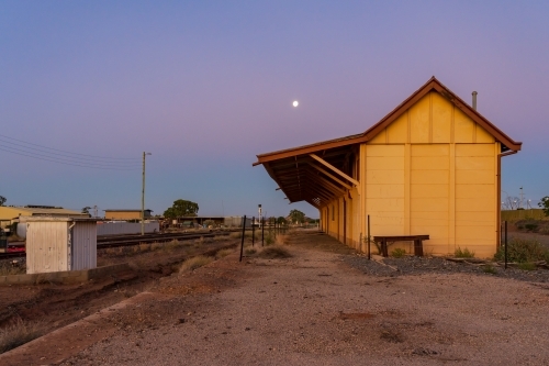 A full moon rising at twilight over an abandoned railway station