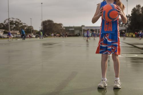A girl facing camera holding the ball for playing netball