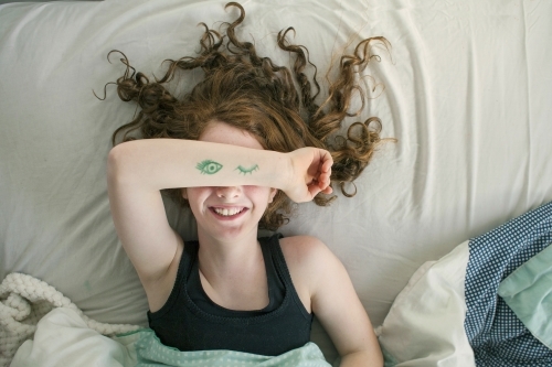 A girl laying in bed pretending to sleep from above