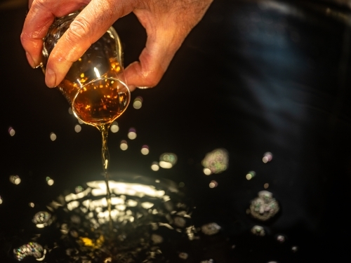 A glass of whisky poured into a whisky still - Australian Stock Image