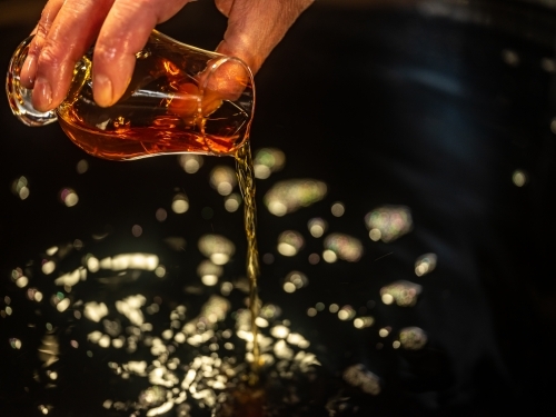 A glass of whisky poured into a whisky still - Australian Stock Image