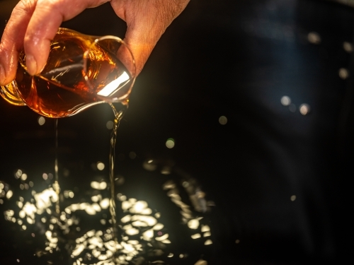 A glass of whisky poured into a whisky still - Australian Stock Image