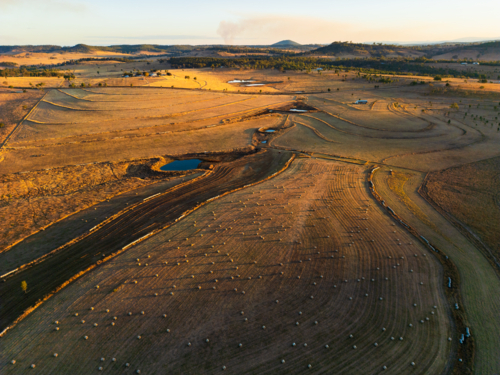 A golden brown coloured paddock dotted with hay bales and small dams - Australian Stock Image