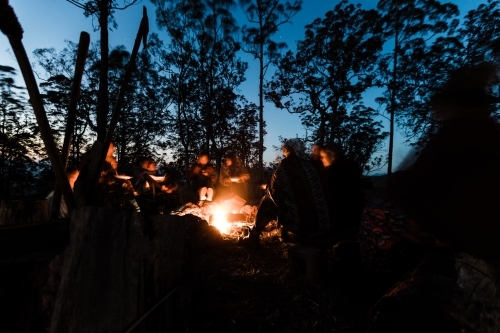 A group of people sitting around a campfire at night relaxing