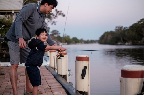 a happy kid being taught how to fish